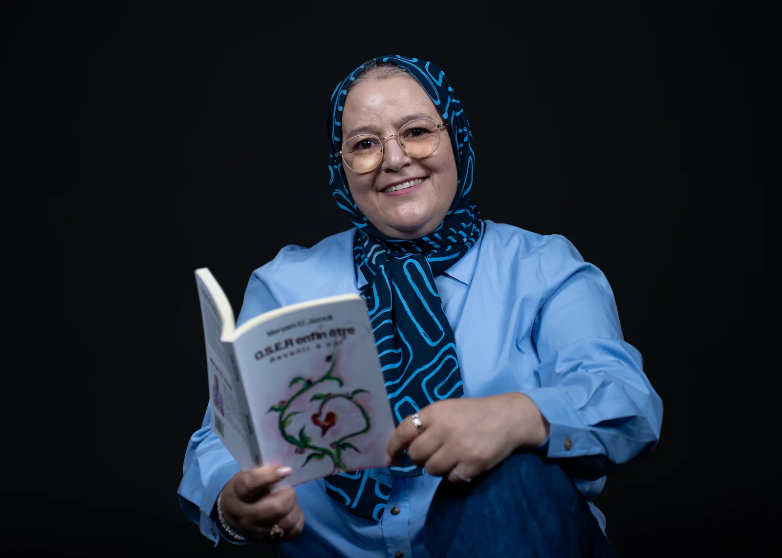 Meryam El Jazouli souriante avec son livre O.S.E.R enfin être, invitant à un appel découverte