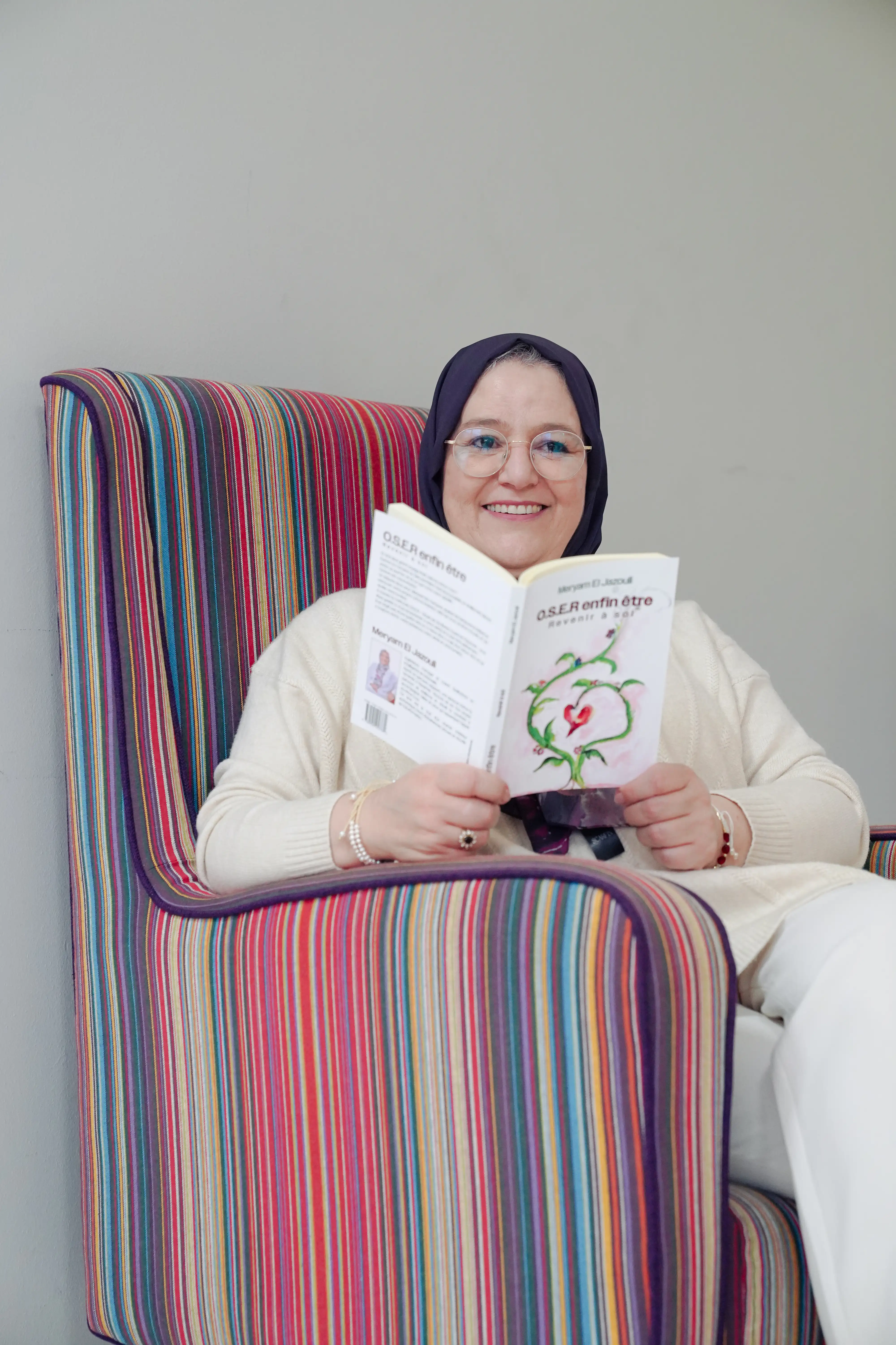 Meryam El Jazouli souriante avec son livre O.S.E.R enfin être, invitant à un appel découverte